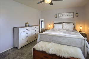 Main floor bedroom featuring ceiling fan and dark carpet