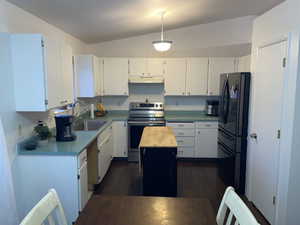 Kitchen with black refrigerator, stainless steel range with electric stovetop, sink, white cabinets, and lofted ceiling