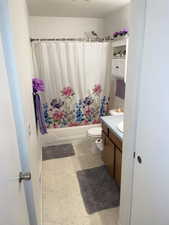 Full bathroom featuring shower / bath combination with curtain, toilet, and vanity