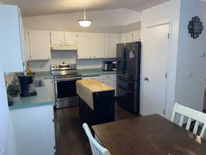 Kitchen with lofted ceiling, electric range, a center island, and black refrigerator with ice dispenser