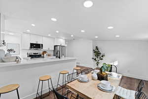 Kitchen with white cabinetry, sink, dark wood-type flooring, kitchen peninsula, and appliances with stainless steel finishes