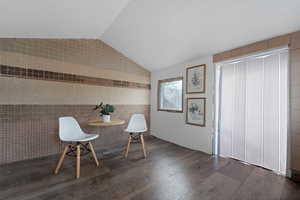 Unfurnished room with lofted ceiling, dark wood-type flooring, and tile walls