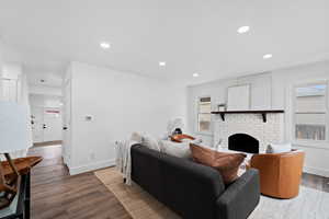 Living room featuring dark hardwood / wood-style floors, a wealth of natural light, and a brick fireplace