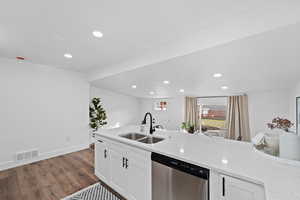 Kitchen featuring dishwasher, dark hardwood / wood-style flooring, white cabinets, and sink