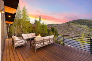 Deck at dusk featuring a mountain view and an outdoor living space with a fire pit