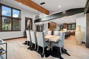 Dining space with sink, lofted ceiling with beams, and light wood-type flooring