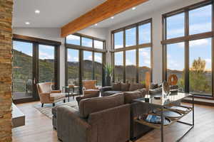 Living room with beam ceiling, a mountain view, plenty of natural light, and light hardwood / wood-style flooring