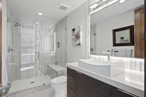 Bathroom with tile patterned flooring, vanity, toilet, and a shower with door