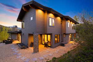 Back house at dusk featuring an outdoor living space, a patio, and central AC unit