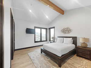 Bedroom featuring lofted ceiling with beams and light hardwood / wood-style flooring