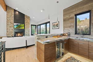 Kitchen with kitchen peninsula, light wood-type flooring, sink, a fireplace, and wine cooler