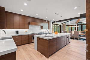 Kitchen featuring an island with sink, decorative light fixtures, light hardwood / wood-style flooring, and sink