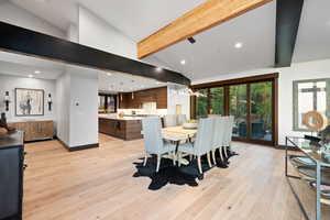 Dining room featuring beam ceiling, sink, high vaulted ceiling, and light hardwood / wood-style flooring