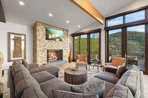 Living room with vaulted ceiling with beams, light wood-type flooring, and a fireplace