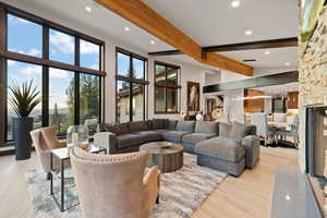 Living room with beam ceiling, high vaulted ceiling, and light hardwood / wood-style flooring