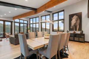 Dining room featuring a mountain view, light hardwood / wood-style floors, an inviting chandelier, and beamed ceiling