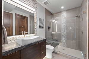 Bathroom with tile patterned flooring, a shower with door, vanity, and toilet