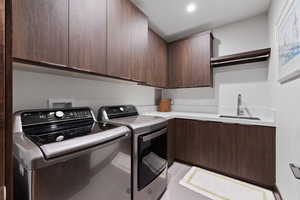 Clothes washing area featuring cabinets, light tile patterned floors, sink, and washing machine and clothes dryer