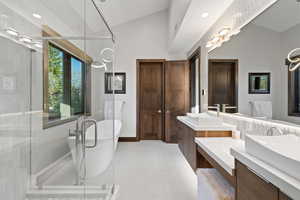 Bathroom featuring tile patterned floors, vanity, shower with separate bathtub, and vaulted ceiling