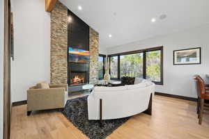 Living room with light wood-type flooring, high vaulted ceiling, and a stone fireplace