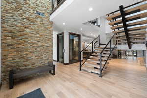 Stairs with hardwood / wood-style floors and a towering ceiling