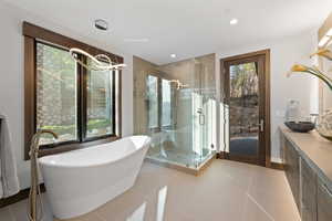 Bathroom featuring tile patterned floors, vanity, plus walk in shower, and a notable chandelier