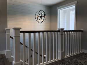 Stairway with hardwood / wood-style flooring and an inviting chandelier