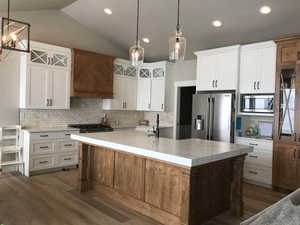 Kitchen featuring stainless steel appliances, white cabinetry, and a center island with sink