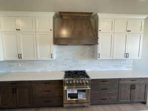 Kitchen featuring tasteful backsplash, light hardwood / wood-style flooring, stainless steel stove, and custom range hood