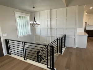 Stairway with hardwood / wood-style flooring and a notable chandelier