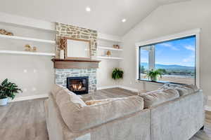 Living room with a fireplace, built in shelves, vaulted ceiling, hardwood / wood-style flooring, and a mountain view