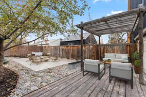 Amazing outdoor entertaining space! Wooden deck with a pergola, outdoor lounge area on the patio, surrounded with multiple raised garden beds