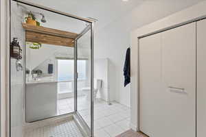 Primary suite bathroom with tile flooring, toilet, an enclosed shower, and large linen closet