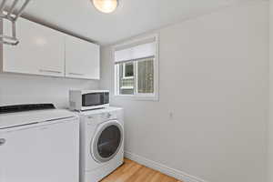 Laundry room featuring cabinets, washing machine and dryer, and storage space