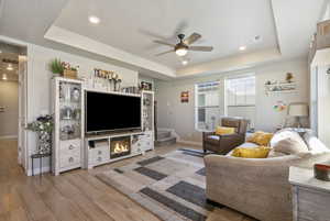 Living room featuring a tray ceiling, ceiling fan, and hardwood / wood-style floors