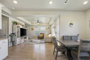 Dining room with a raised ceiling, ceiling fan, and light hardwood / wood-style flooring