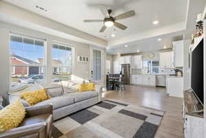 Living room with light wood-type flooring, ceiling fan, and sink