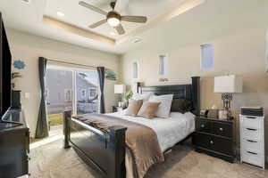 Carpeted bedroom featuring a raised ceiling, ceiling fan, and access to outside