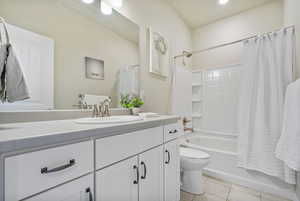 Full bathroom with toilet, shower / tub combo, vanity, and tile patterned floors