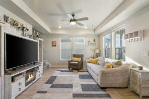 Living room featuring a tray ceiling, light hardwood / wood-style flooring, and ceiling fan