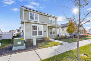 View of property featuring solar panels and a front lawn