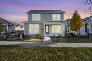 View of front property with a lawn and solar panels