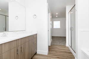 Bathroom featuring hardwood / wood-style floors, vanity, and an enclosed shower