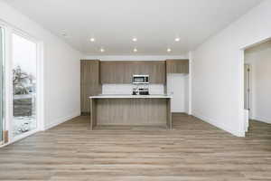 Kitchen with an island with sink, light wood-type flooring, and appliances with stainless steel finishes