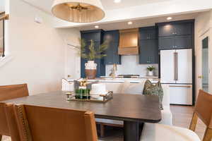 Kitchen featuring backsplash, premium range hood, sink, high end white fridge, and light wood-type flooring