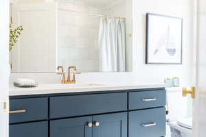 Bathroom with vanity, toilet, and curtained shower