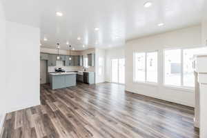 Kitchen featuring stunning cabinetry, dark wood-type flooring, hanging light fixtures, a kitchen island, and appliances with stainless steel finishes