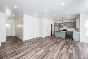 Kitchen with dark hardwood / wood-style flooring, decorative light fixtures, stainless steel range oven, and a kitchen island