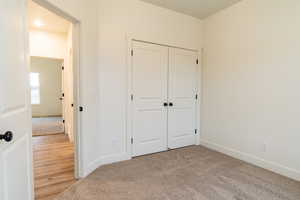 Unfurnished bedroom featuring a closet and light colored carpet