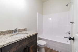 Full bathroom featuring hardwood / wood-style flooring, vanity, shower / bathtub combination, and toilet